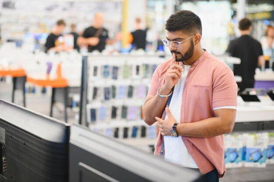 A man is looking to buy a phone stand at a gadget shop