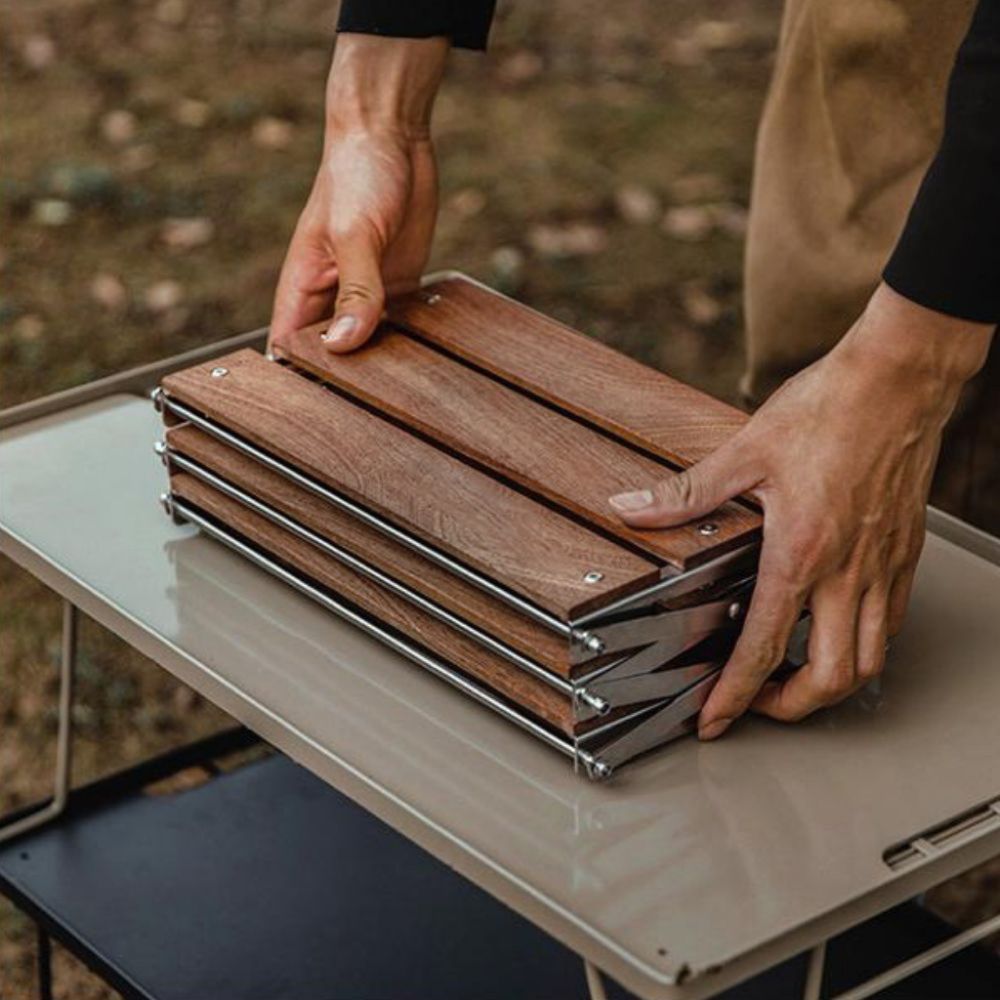 A person's hands are folding the compact Super Wooden Desk Shelf on a white table outdoors | Cyber Vintage